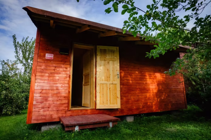 Cabaña del Amor para un retiro de oscuridad bajo un manzano, con la puerta abierta