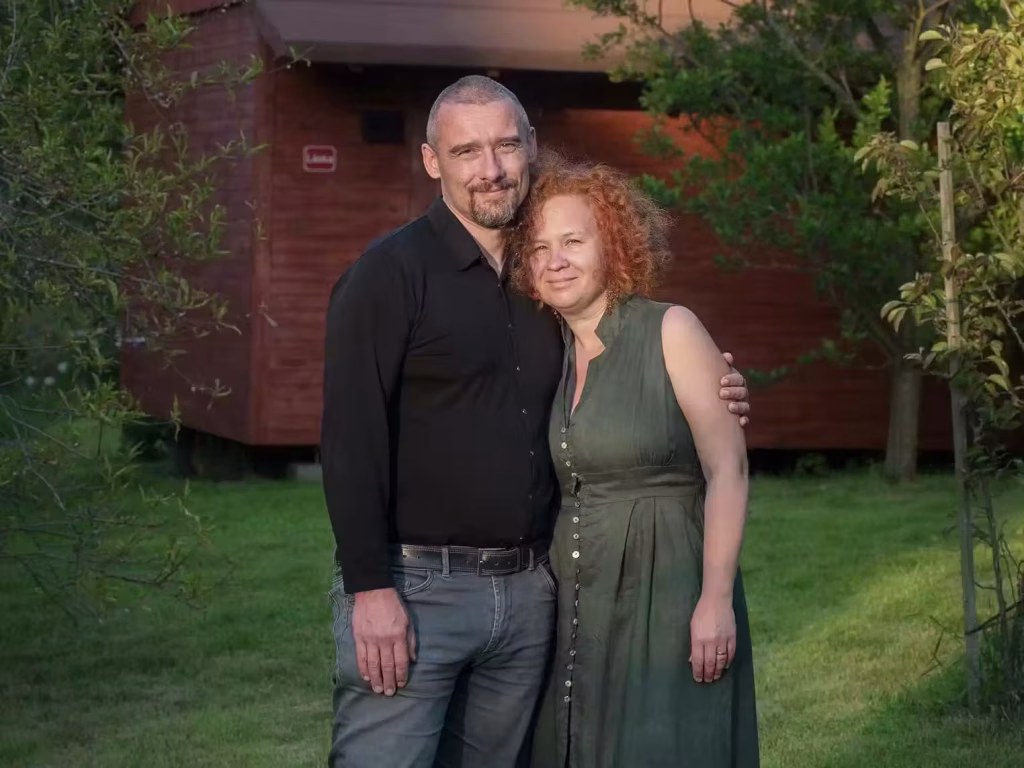 Tom y Lenka, guías del retiro de oscuridad, delante de una cabaña